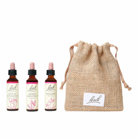 There are three dropper bottles with essences from left to right: Bach™  Original Flower Remedies Star of Bethlehem, Bach™ Original Flower Remedies Sweet Chestnut and Bach™ Original Flower Remedies Willow. Next to the last essence, there is a burlap bag with the Bach™ logo on it.