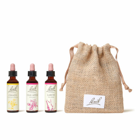 There are three dropper bottles  with essences from left to right: Bach™ Original Flower Remedies Cerato, Bach™ Original Flower Remedies  Crab Apple and Bach™ Original Flower Remedies Larch. Next to the last essence there is a burlap bag with the Bach™ logo on it.