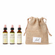 There are three dropper bottles with essences from left to right: Bach™ Original Flower Remedies Gentian, Bach™ Original Flower Remedies Honeysuckle and Bach™ Original Remedies Wild Oat. Nest to the last essence there is a burlap bag with the Bach™ logo on it.