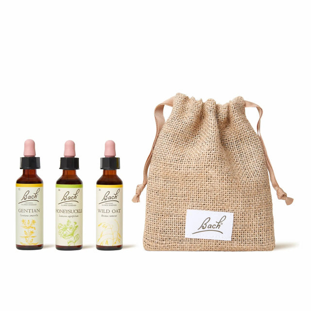 There are three dropper bottles with essences from left to right: Bach™ Original Flower Remedies Gentian, Bach™ Original Flower Remedies Honeysuckle and Bach™ Original Remedies Wild Oat. Nest to the last essence there is a burlap bag with the Bach™ logo on it.