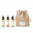 Three are three dropper bottles with essence from left to right: Bach™  Original Flower Remedies Mustard, Bach™  Original Flower Remedies Pine and Bach™  Original Flower Remedies Gorse. Next to the last essence there is a burlap bag with the Bach™  logo on it.