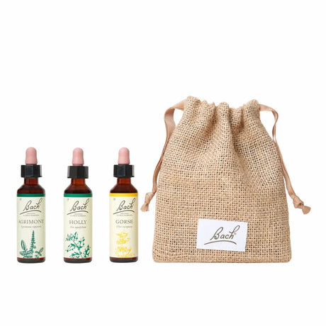 There are three dropper bottles with essences from left to right: Bach™  Original Flower Remedies Agrimony, Bach™  Original Flower Remedies Holly and Bach™  Original Flower Remedies Gorse. Next to the last essence there is a burlap bag wit the Bach™  logo on it.