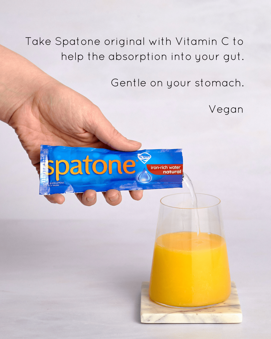 Infographic showing a glass of orange juice and a hand adding one Spatone Sachet and on the top  says" Take Spatone original with Vitamin C to help the absorption into your gut, Gently on your stomach, Vegan"