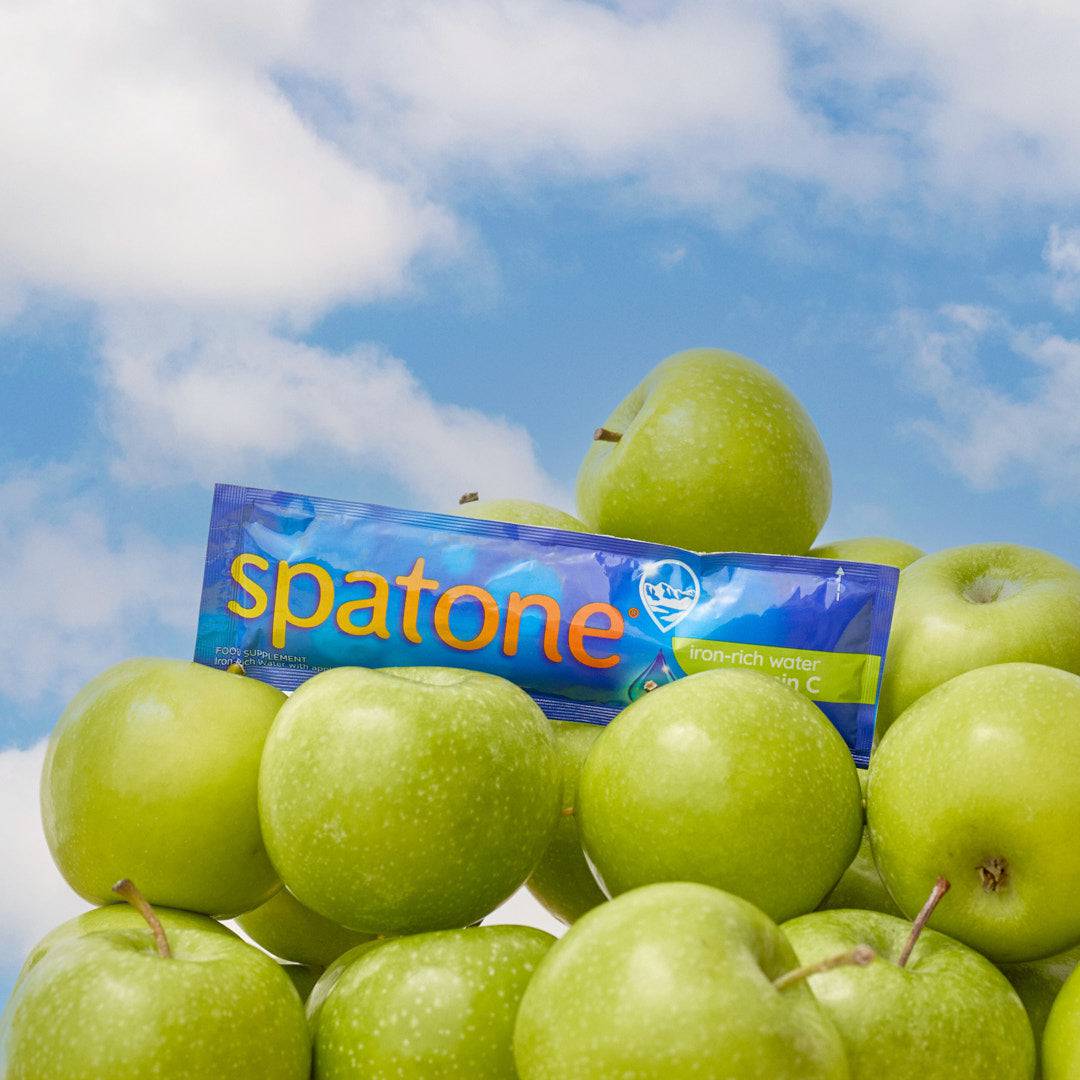 Sky background with clouds, green apples on the front of the image and a Spatone envelope on the top. 