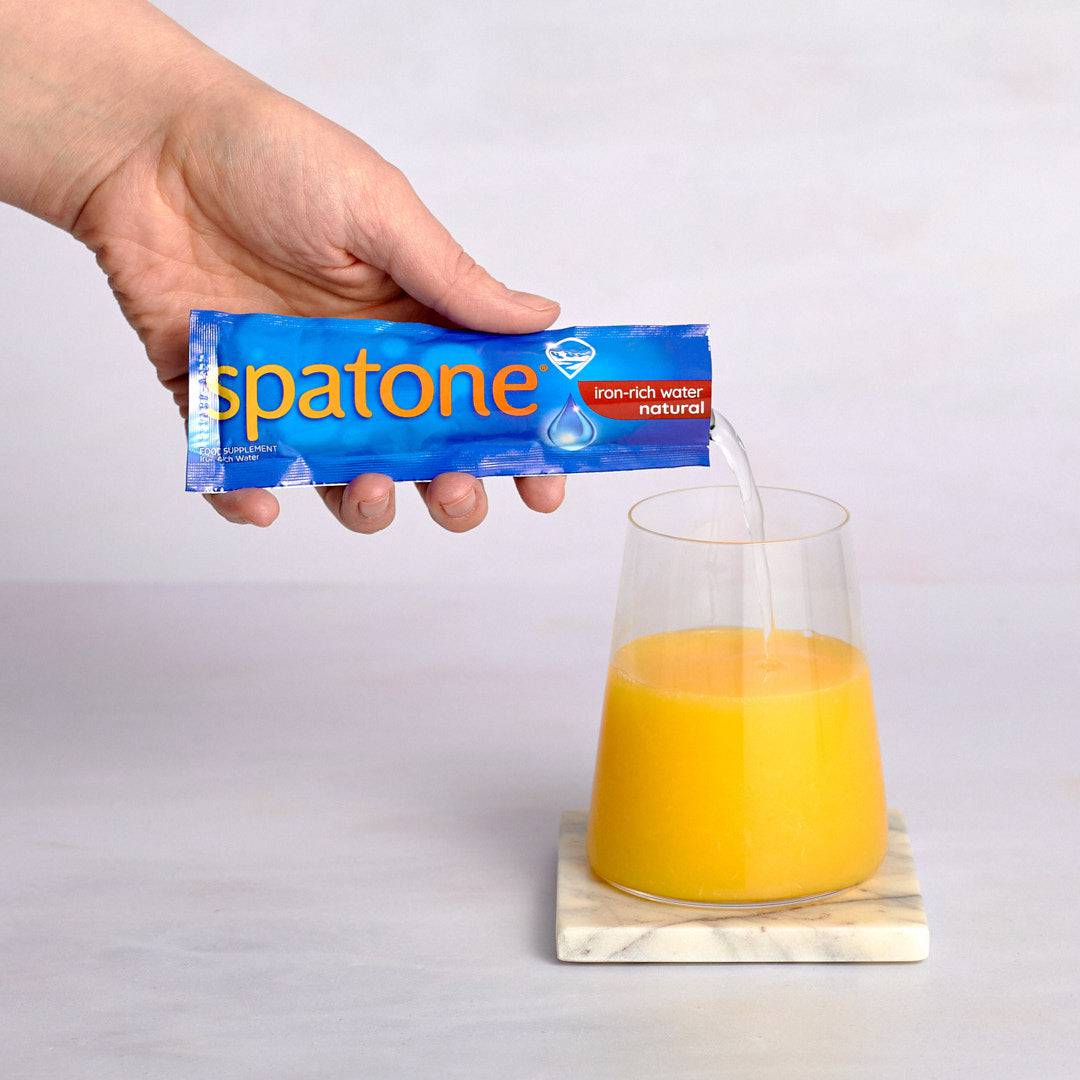  A person adding Spatone Sachet to a glass of orange juice 
