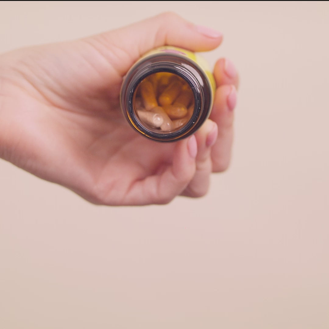 Video of a woman holding Rescue Balance & Positivity capsules in one hand, shaking the bottle and pulling out three capsules on her other hand.