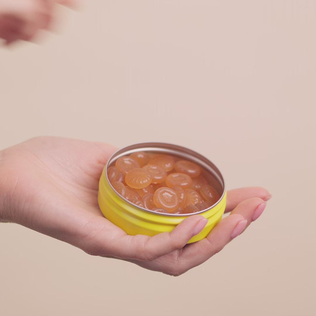  Video of an open tin with pastilles in it, one hand taking a pastille out of the can and then touching it for a second between the fingers.