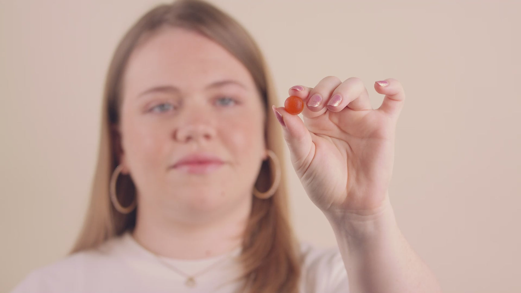 Video of a woman taking a gummie in her hand and then eating it.