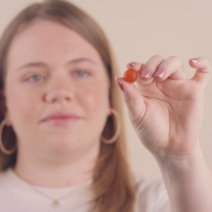Video of a woman taking a gummie in her hand and then eating it.